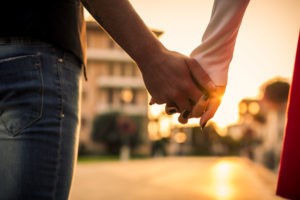 Couple hand by hand at Sunset.