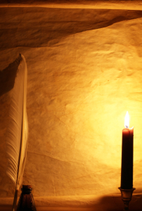 Paper, quill, & ink lit by candle