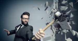 Young employee smashing a wall with a hammer