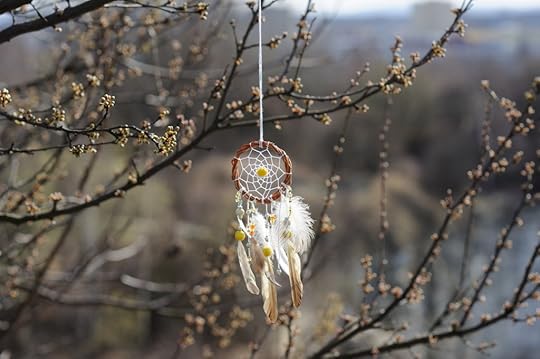 Handmade native american dream catcher on background of rocks and lake. Tribal elements, feathers