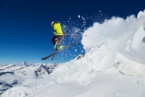 Alpine skier skiing downhill, blue sky on background