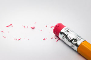 Using a pencil to erase a mistake on a sheet of white paper