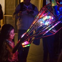 A small girl pets the nose of an electronic giraffe robot.