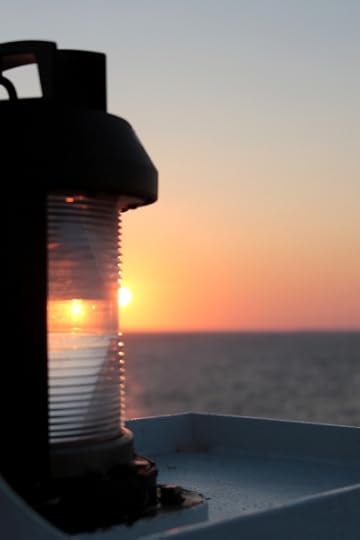 Artsy shot of the rising sun refracting through a lamp at the front of the ship.