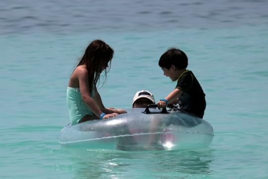 SteelyKid and The Pip floating in a tube at the Castaway Cay beach. With just-barely-visible Kate.