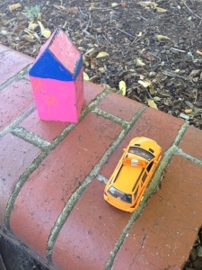 Toy house and toy car on a brick fence