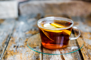 A cup of tea with lemon on rustic wooden background