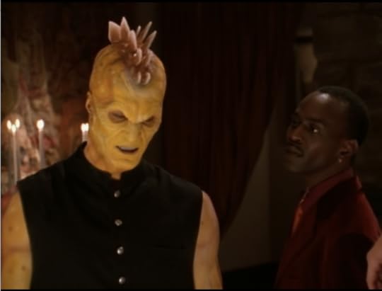 Kulak is a yellow dude with two ridges of stegosaurus type spines down the middle of his head, like a mohawk. Mr. Trick is looking at him critically.