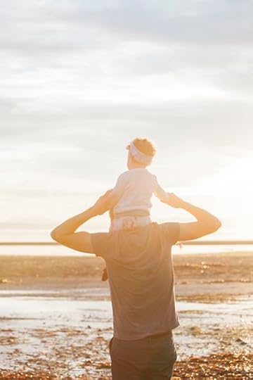 Dad carries his toddler daughter on his shoulders on the beach: 