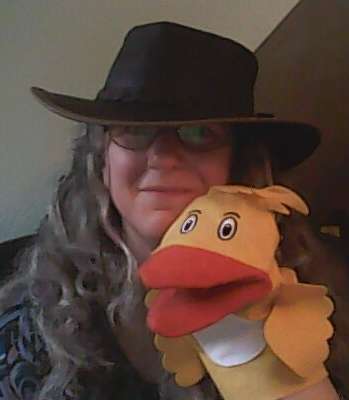 image of author wearing a hat and holding a duck hand puppet