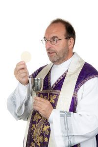 a catholic priest with chalice and host at communion