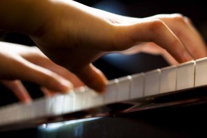 Closeup of a child's hands playing the piano. Horizontally framed shot.