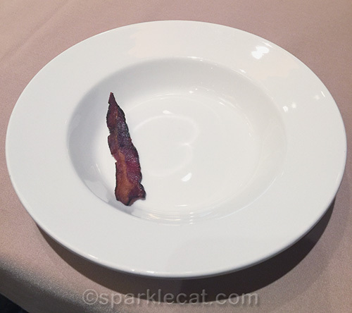 half a strip of bacon on a plate