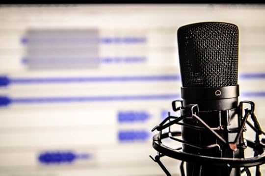 A microphone in front of a computer screen showing sound recording data
