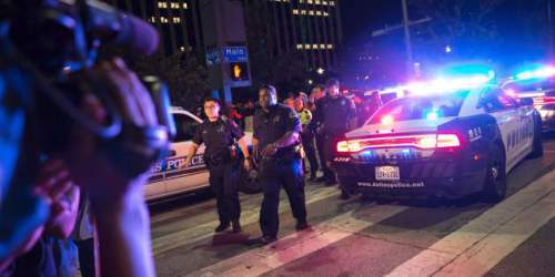 Bystanders stand near pollice baracades following the sniper shooting in Dallas on July 7, 2016. A fourth police officer was killed and two suspected snipers were in custody after a protest late Thursday against police brutality in Dallas, authorities said. One suspect had turned himself in and another who was in a shootout with SWAT officers was also in custody, the Dallas Police Department tweeted. / AFP / Laura Buckman (Photo credit should read LAURA BUCKMAN/AFP/Getty Images)