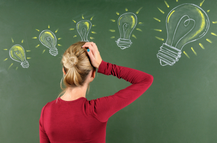 Woman scratching her head at light bulbs on chalkboard