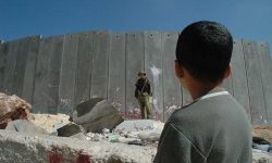 A Palestinian boy and an Israeli soldier by Israel's illegal separation wall in the West Bank. (Justin McIntosh/CC BY 2.0)