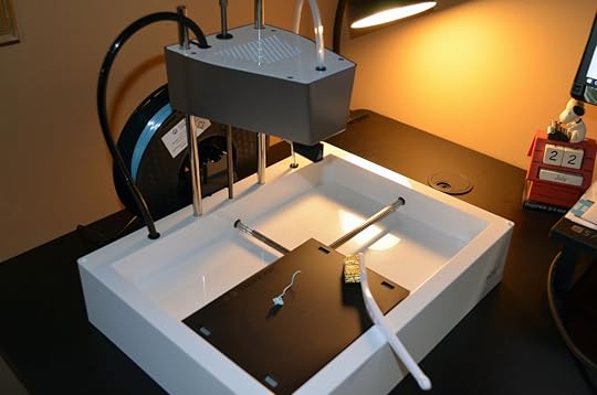 Using the wire brush to scrape off extruded filament remnants on the print head.