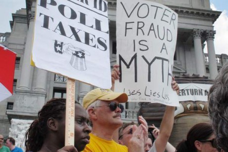 Demonstrators hold signs on the steps of the Pennsylvania Capitol to protest the state's new voter identification law.
