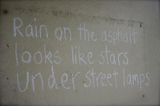 Rain on the asphalt looks like stars under street lamps. Graffiti chalk poem.