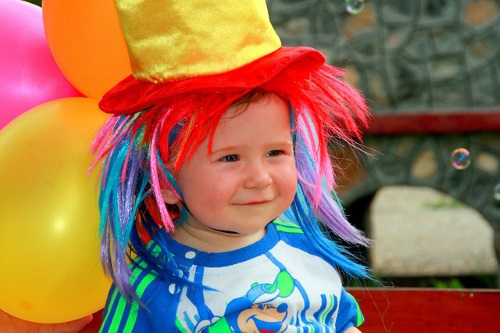 Baby wearing clown hat.