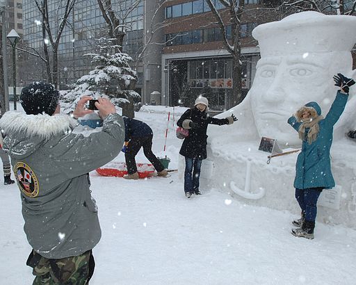 US Navy 120204-N-ZI955-042 Navy Misawa Snow Sculpture Team leader photographs festival attendees in front of the Lone Sailor snow sculpture