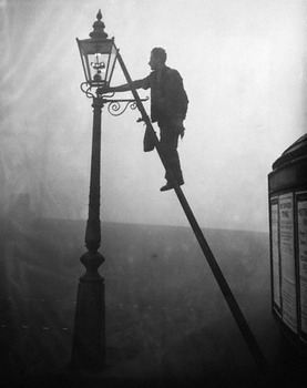 A lamplighter on a ladder, lighting a gas street light.
