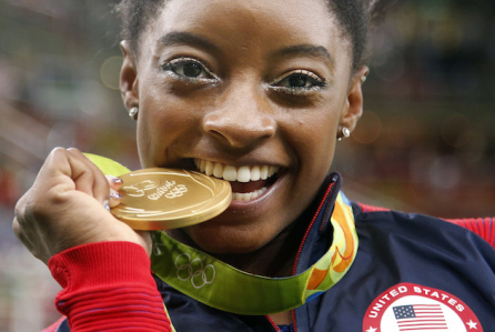 United States' Simone Biles bites her gold medal for the artistic gymnastics women's individual all-around final at the 2016 Summer Olympics in Rio de Janeiro, Brazil, Thursday, Aug. 11, 2016. (AP Photo/Dmitri Lovetsky)