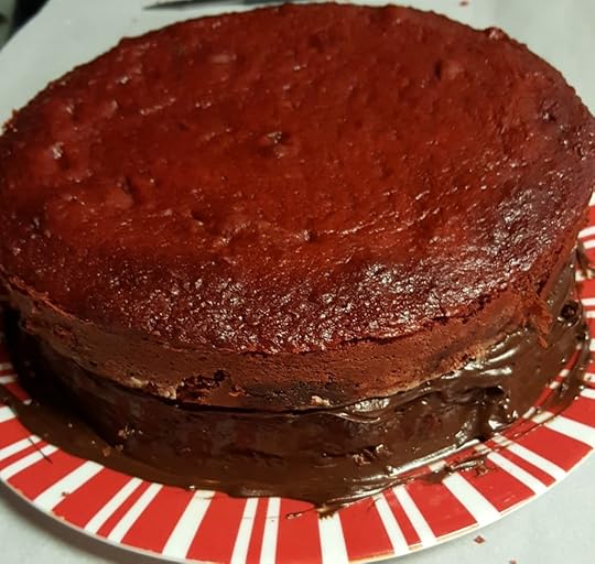 Two cakes stacked on top of each other. The bottom is frosted in chocolate frosting, the top is unfrosted.