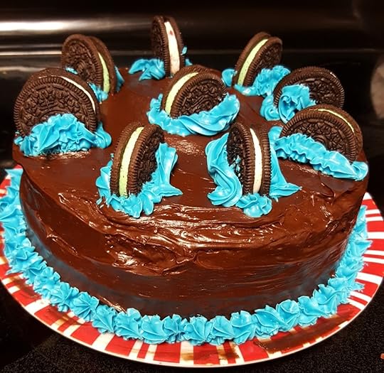 A double-layer chocolate cake with Oreos standing on their sides, propped up by mounds of blue frosting. The Oreos form a circle around the outside, with one in the middle.