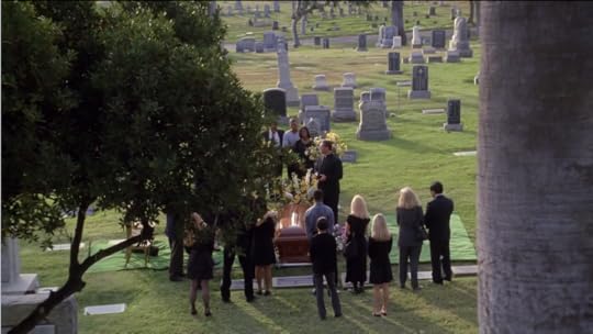 A shot from above of a cemetery, with mourners gathered around a casket.