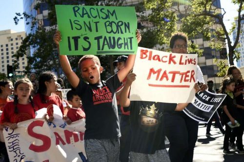 Kaden Pagani, 8, left, and his brother Kingston, 6, carry signs as they march down Broadway toward Frank Ozawa Plaza during a Black Lives Matters protest in Oakland on Thursday, July 21, 2016. Image by Michael Short.