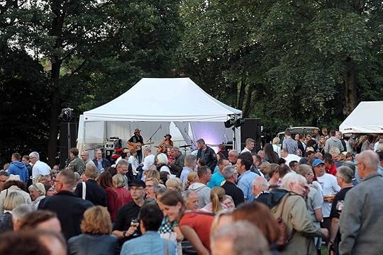 Sehr viele Menschen, hinten unter einem Pavillon eine Band.