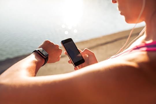 44972561 - sportswoman looking at smartwatch and holding smart phone in her other hand, outdoors. fitness female setting up her smartwatch for her run.
