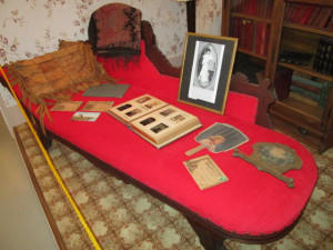 The fainting couch in the living room with keepsakes of the family. with a book case behind the couch.