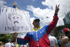 A protester holds a sign with a drawing depicting Venezuela's President Nicolas Maduro and a message that reads in Spanish;