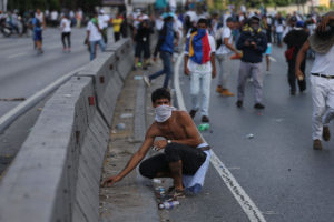 An anti-government demonstrator picks up a stone during a protest in Caracas, Venezuela, Thursday, Sept. 1, 2016. Venezuela's opposition is vowing to keep up pressure on President Nicolas Maduro after flooding the streets of Caracas with demonstrators Thursday in its biggest show of force in years. Protesters filled dozens of city blocks in what was dubbed the