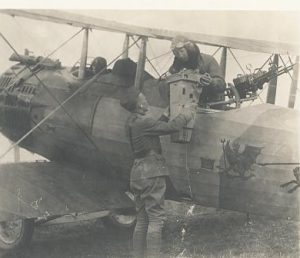 Maj. J.N. Reynolds, a pilot in the 91st. Aero Squadron, lifts an aerial camera into his bi-plane with help from a bystander, 1917-1918. U.S. Signal Corps photo, Prints and Photographs Division.