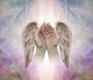 Angelic helping hands - cupped hands with finely detailed Angel wings on either side, on an intricate ethereal patterned background with a central light shaft and copy space