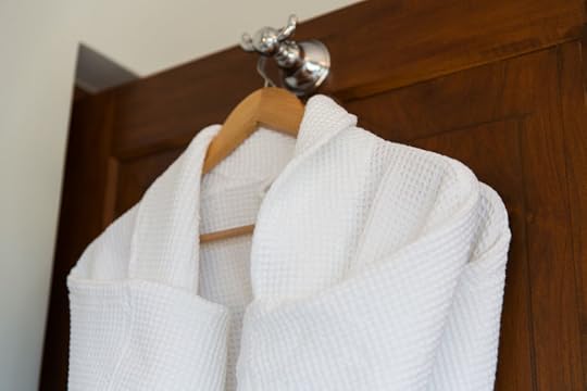 61033443 - bath, clothes, hygiene and luxury concept - close up of two white bathrobes hanging on wooden hanger at home or hotel