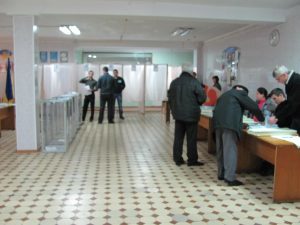A well-organized voting station, with curtained voting booths and ballot boxes readily visible to prevent mischief.