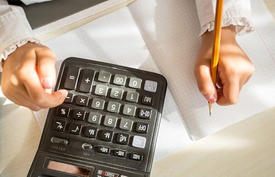 34034279 - closeup shot of child using calculator while doing homework