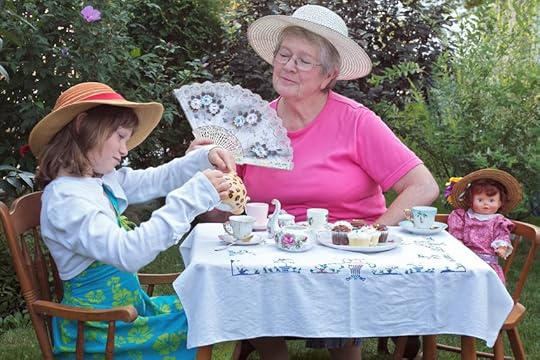14570378 - a charming spring garden is a perfect setting for a loving grandmother and her 6 year old granddaughter to have a tea party, accompanied by a vintage doll. accessories include a lace fan, pretty straw hats, bright pastel dresses, delicate antique china te