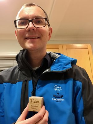 Picture of Tom in his Hackathon jacket with the 1st place trophy