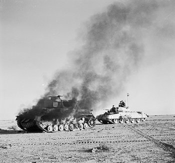 British Crusader tank passing a burning German Panzer IV tank in North Africa during Operation Crusader, 27 Nov 1941 (Imperial War Museum)