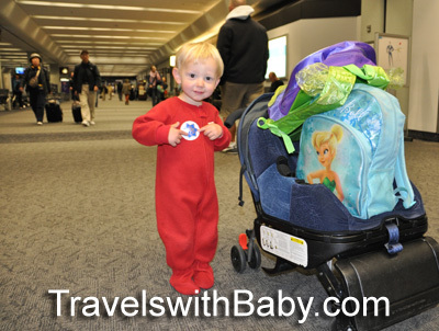 toddler at the airport for holiday travel in red pajamas from travelswithbaby.com