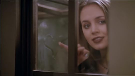 Faith is standing behind a window, having just drawn a heart on the glass. She's looking at Buffy with a very romantic look.