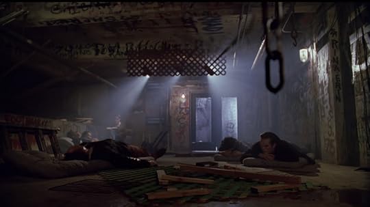 A bunch of vampires are sleeping on mattresses on the floor of a gross looking warehouse. One of them is reading in the corner.