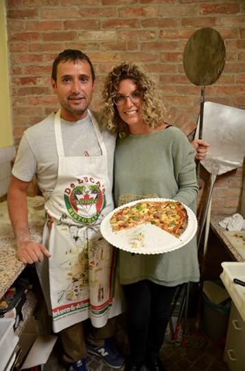 Giorgio Faccenda, with the aid of his wife Cristina Deltetto, keeps the supply of pizzas going on Christmas Eve in the Deltetto winery's tasting room. 