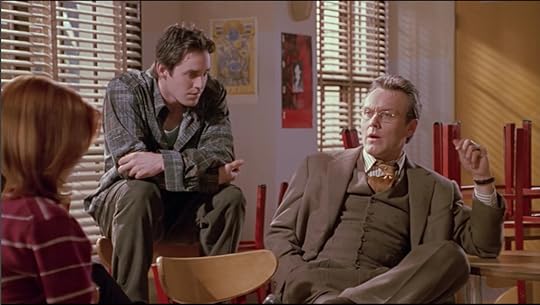Giles sits beside Xander. Giles is now also making a face that indicates he understands what Xander's been trying to say.